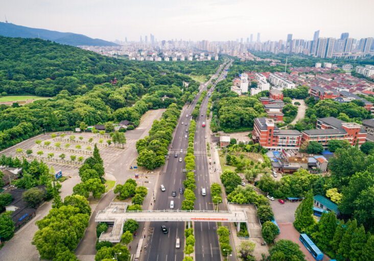 A highway next to a city surrounded with trees